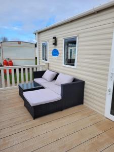 a patio with a couch and a table on a deck at K & K Caravan Southview in Skegness