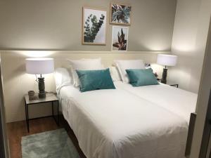 a bedroom with a large white bed with two lamps at Apartamentos Castrón Douro in Santiago de Compostela