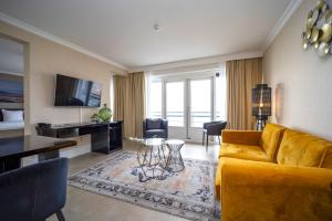 een woonkamer met een gele bank en een televisie bij Fletcher Hotel-Restaurant Arion-Vlissingen in Vlissingen