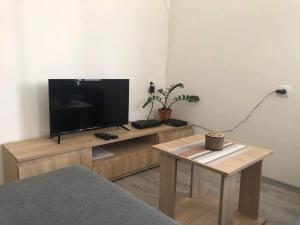 uma sala de estar com uma televisão de ecrã plano num suporte de madeira em Apartman Arthur em Kikinda