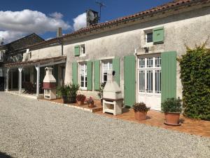 a building with green and white doors and potted plants at Les Vieilles Ombres in Bagnizeau