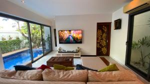 a living room with a couch and a tv on a wall at Villa Soi Mangosteen in Rawai Beach