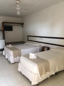 Duas camas num quarto com paredes brancas em Mar & Sol Praia Hotel em Prado