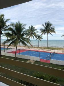 a tennis court next to the beach with palm trees at Mar & Sol Praia Hotel in Prado