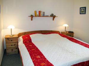 a bedroom with a bed with a red and white blanket at Holiday Home Katamaran I by Interhome in Burhave