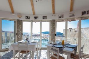 a dining room with white tables and chairs and windows at Spa Resort Luxury Apartments in Budva