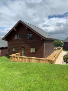 a large brown house with a wooden deck at Retallack Resort 4 bedroom lodge - Hot Tub for hire on request -Pool & Spa in Padstow