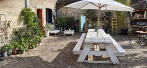 a picnic table with an umbrella in a courtyard at Les Petites Mirabelles - À 9mn du ZooParc de Beauval - Gare à 200m - Route des Châteaux de la Loire in Noyers-sur-Cher