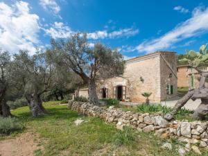 una antigua casa de piedra con árboles y una pared de piedra en Holiday Home Can Tiona by Interhome, en Andratx