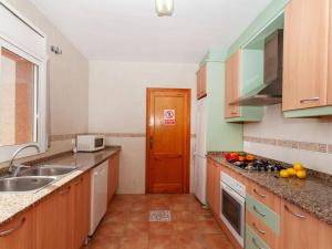 eine kleine Küche mit Holzschränken und einer Spüle in der Unterkunft Villa Villa Cala Vidre B by Interhome in Les tres Cales