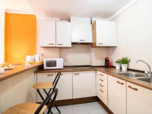 a kitchen with white cabinets and a table and a microwave at Apartment Club Nautic-12 by Interhome in Empuriabrava