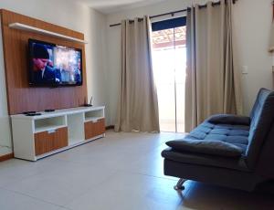 ein Wohnzimmer mit einem Sofa und einem Flachbild-TV in der Unterkunft Apartbuzios - Apartamentos Completos Búzios - 600mt Rua das Pedras in Búzios
