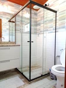 a glass shower in a bathroom with a toilet at Apartbuzios - Apartamentos Completos Búzios - 600mt Rua das Pedras in Búzios