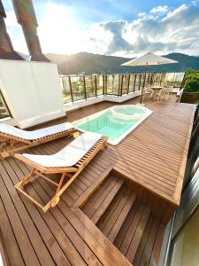 a deck with a pool and chairs and an umbrella at Cobertura Velejar em Condomínio Clube - com Área de Lazer in Governador Celso Ramos +32 photos
