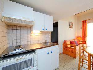 a kitchen with white cabinets and a stove top oven at Holiday Home Les Maisons du Golf by Interhome in Cap d'Agde