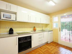 a kitchen with white cabinets and a black dishwasher at Holiday Home Puig Dels Daus by Interhome in Calonge
