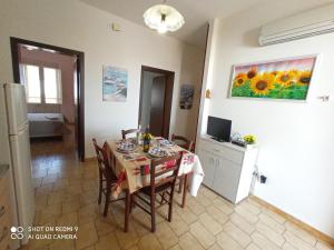 a dining room with a table with chairs and a painting on the wall at Residence Poseidon in Lido Marini