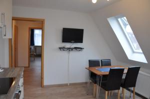 uma sala de jantar com uma mesa e uma televisão na parede em Ferienhaus Nordstrand Whg 4 em Baltrum