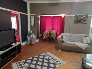 een woonkamer met een bank en roze gordijnen bij Karoo Refresh Cheerful 2 Bedroom House in Oudtshoorn