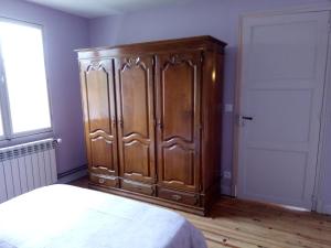 a large wooden cabinet in a room with a bed at chez Doris et Alain in Lannemezan