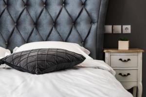 a bed with a black padded headboard and a pillow at Dallure Boutique Brasov in Braşov