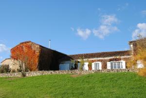 a building with a stone wall next to a green field at Le Château de Roquebère in Condom