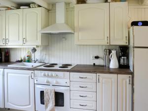 La cuisine est équipée de placards blancs et d'un four avec plaques de cuisson blanches. dans l'établissement Chalet Solskinn - SOW037 by Interhome, à Kvås
