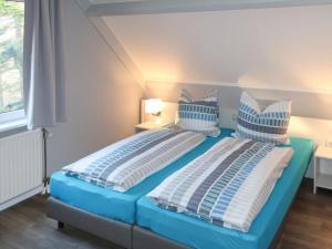 a bedroom with two beds with blue and white pillows at Holiday Home Nordseeblick by Interhome in Butjadingen OT Tossens