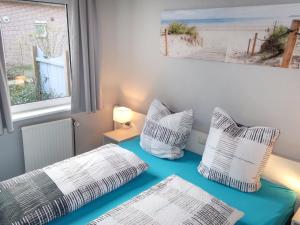 a room with two beds with pillows and a window at Holiday Home Nordseeblick by Interhome in Butjadingen OT Tossens