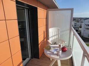 a chair on a balcony with a book and an apple at Studio Les Allées du Port by Interhome in Saint Malo