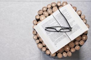 a book and a pair of glasses on a bunch of wood beads at Almyra Guest Houses in Paraga