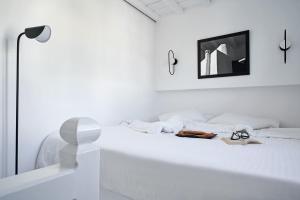 a white bedroom with a white bed with a mirror at Almyra Guest Houses in Paraga