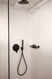 a shower in a white wall with a black shower head at Almyra Guest Houses in Paraga