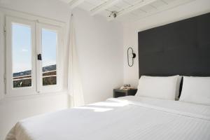 a white bed sitting in a bedroom next to a window at Almyra Guest Houses in Paraga