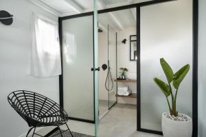 a glass shower door in a bathroom with a chair at Almyra Guest Houses in Paraga