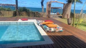 a bed next to a swimming pool next to the beach at Villa do Sossego - Caraíva in Caraíva