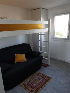 a bedroom with a bunk bed and a black couch at Appartement Front de mer - Vue Ocean in Lacanau-Océan