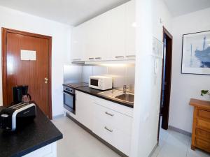a kitchen with white cabinets and a sink and a microwave at Apartment Esmeralda 02 by Interhome in Calpe