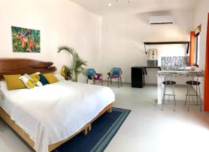 a bedroom with a bed and a kitchen with chairs at Villas Chital Bacalar in Bacalar
