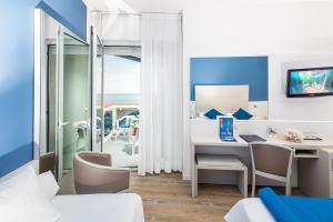 a room with a desk and a table with chairs at Majestic Beach Hotel & Wellness in Bibione
