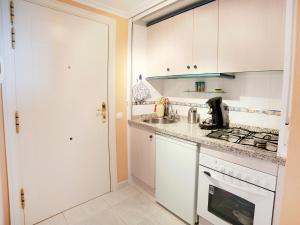 una cucina con armadi bianchi, lavandino e piano cottura di Apartment Turquesa Beach 03 by Interhome a Calpe