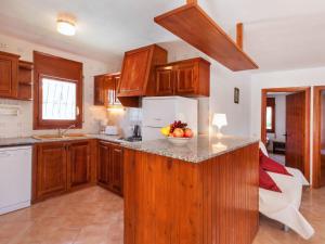 una cocina con armarios de madera y un bol de fruta en la barra en Villa Villa Zozo by Interhome, en L'Ametlla de Mar