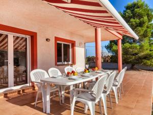 a table with white chairs and an umbrella on a patio at Villa Villa Malva I by Interhome in Les tres Cales