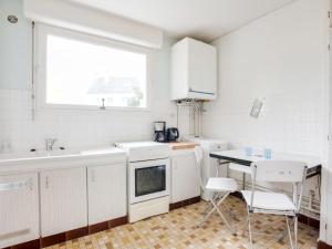uma cozinha com armários brancos, uma mesa e uma janela em Holiday Home Penthievre by Interhome em Légenès