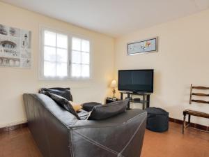 ein Wohnzimmer mit einem Ledersofa und einem TV in der Unterkunft Holiday Home Penthievre by Interhome in Légenès