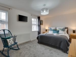 um quarto com uma cama, uma cadeira e uma televisão em Holiday Home Glynn Terrace by Interhome em Padstow