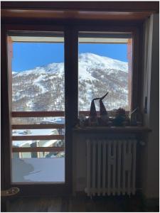 una ventana con vistas a una montaña nevada en Bilocale con vista a Sestriere en Sestriere