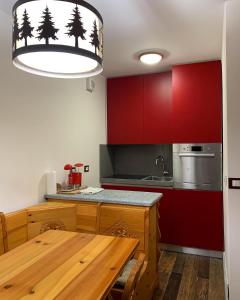 una cucina con tavolo in legno e armadietti rossi di Bilocale con vista a Sestriere a Sestriere