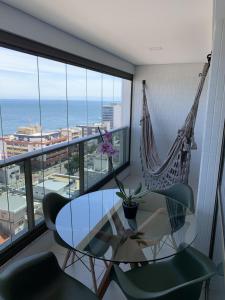 Habitación con mesa de cristal, sillas y hamaca. en BARRA 535 vista mar moderno e confortável, en Salvador