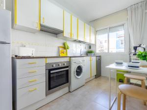 カンブリルスにあるApartment Carme by Interhomeのキッチン(黄色のキャビネット、洗濯機、乾燥機付)